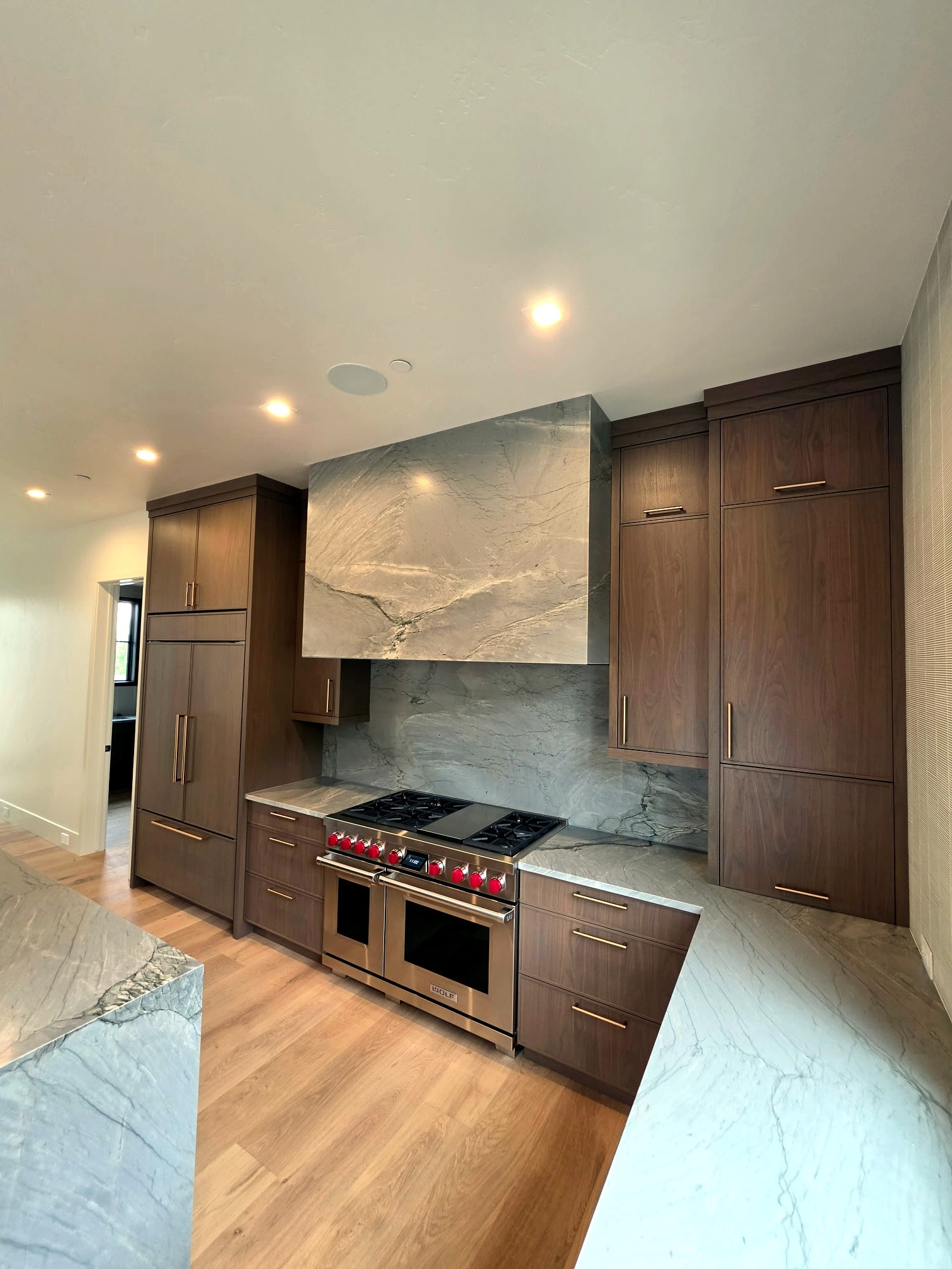 Hillside Haven kitchen — dark wood cabinetry with marble hood surround and professionally painted walls