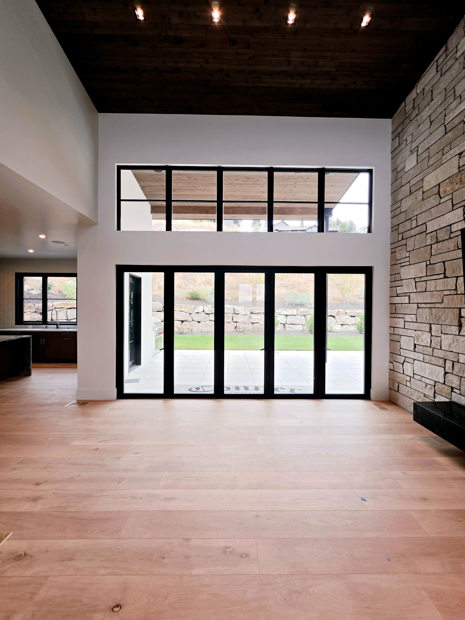Hillside Haven great room — soaring ceilings, black-framed glass doors, and professionally painted walls