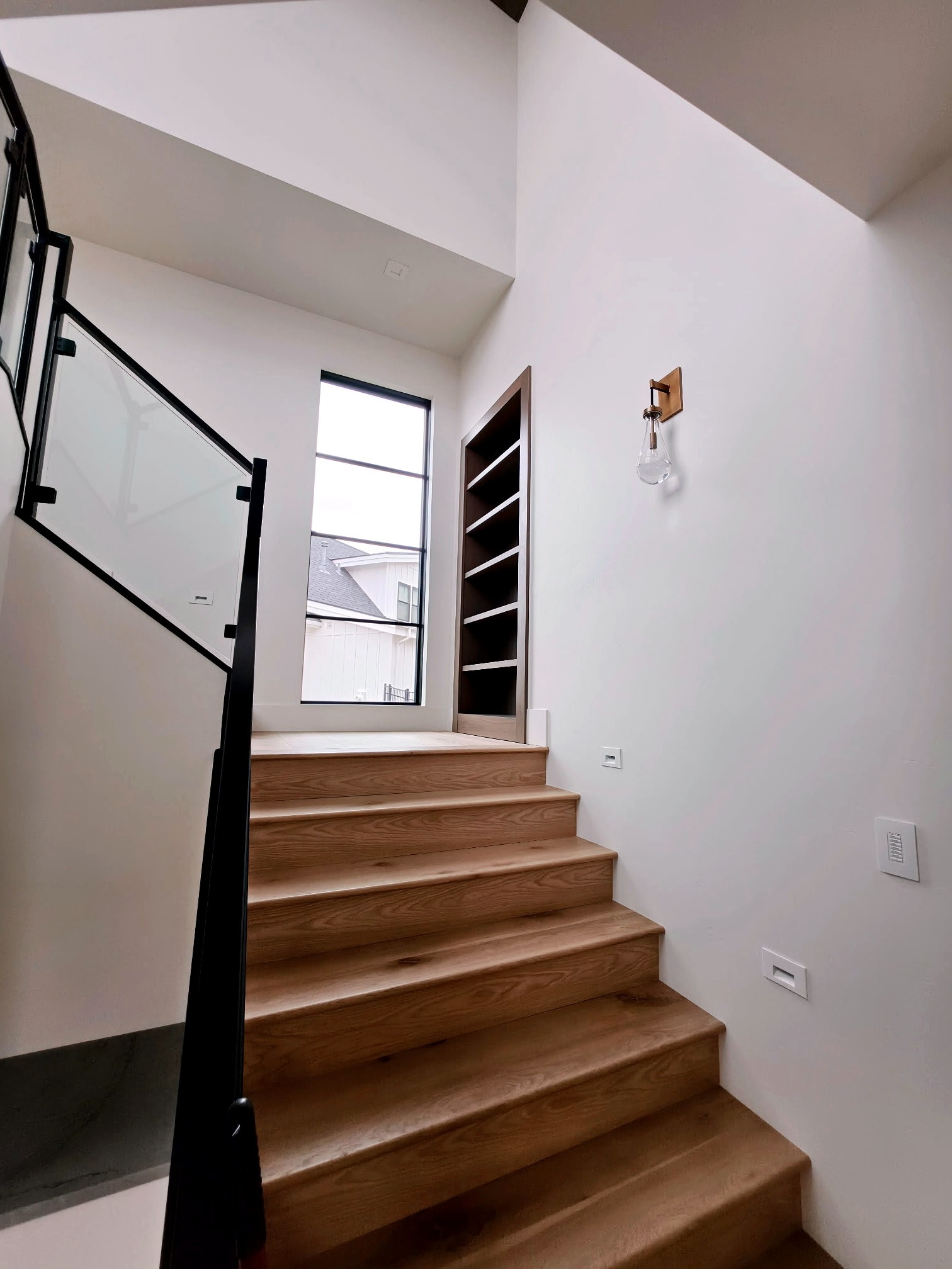 Hillside Haven stairway — wood treads, glass railing, and crisp painted walls and trim